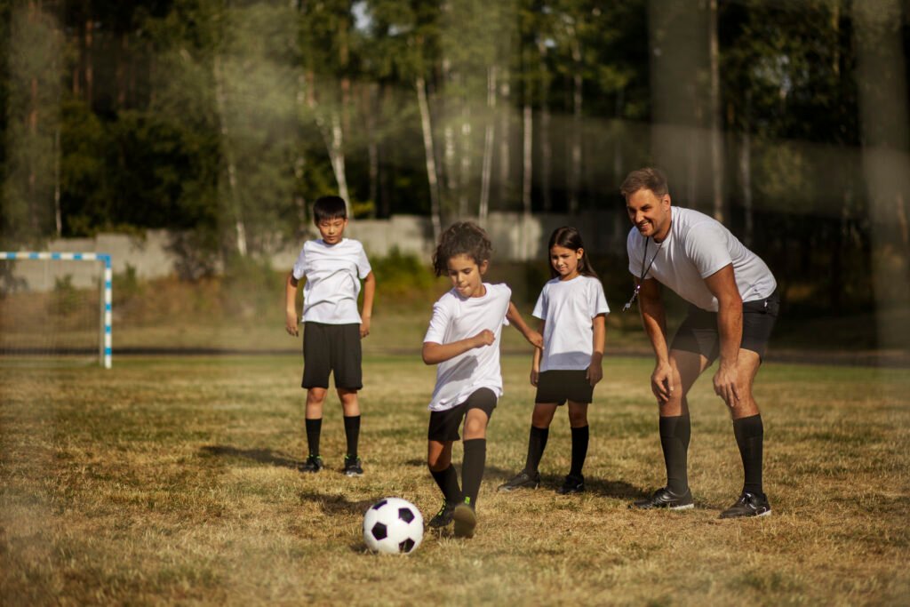 kids playing football supervised by football trainer